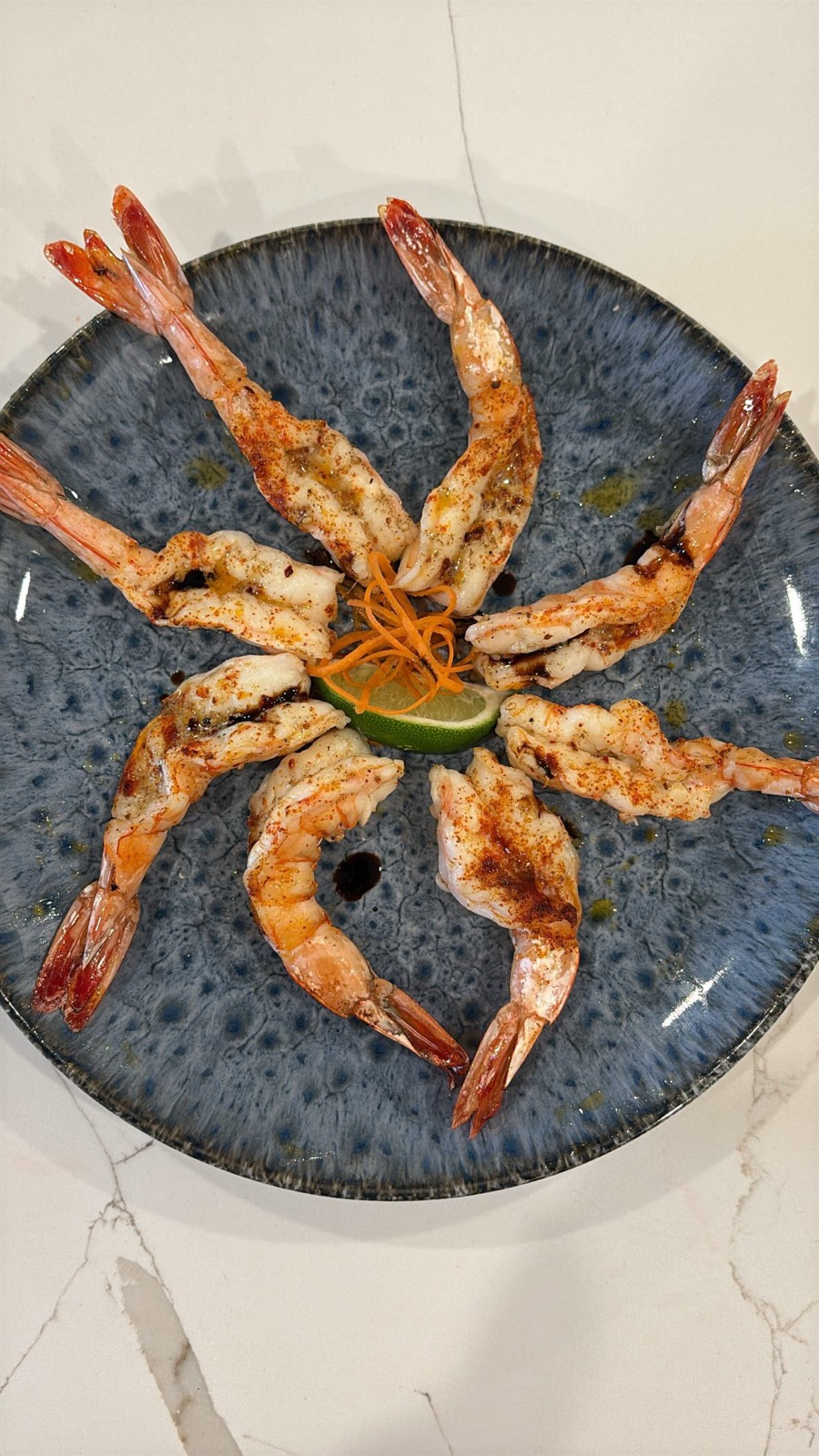 Grilled prawns arranged around charred lime