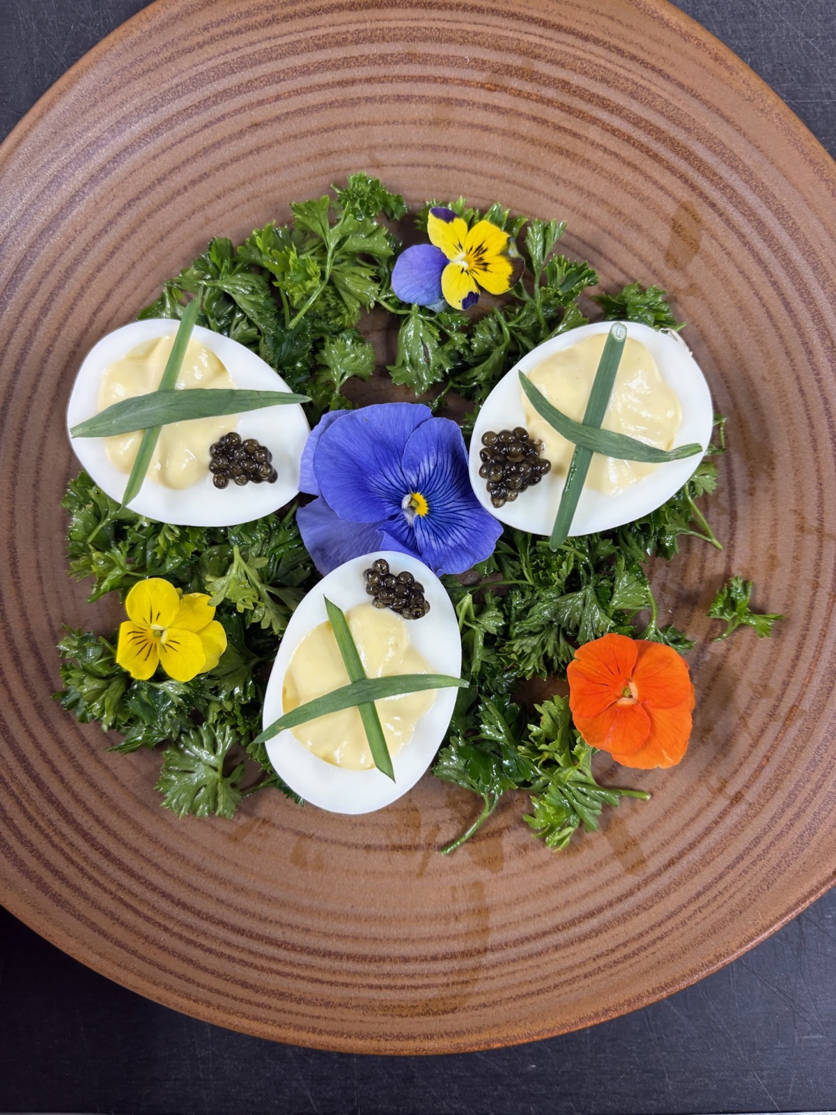 Deviled eggs with caviar and pansies on a bed of parsley